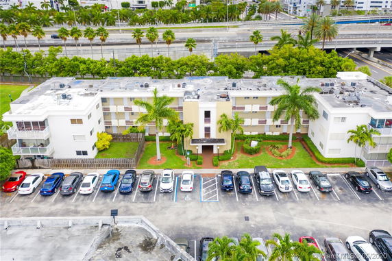 Front view of a multi-story apartment building with a parking area in front.