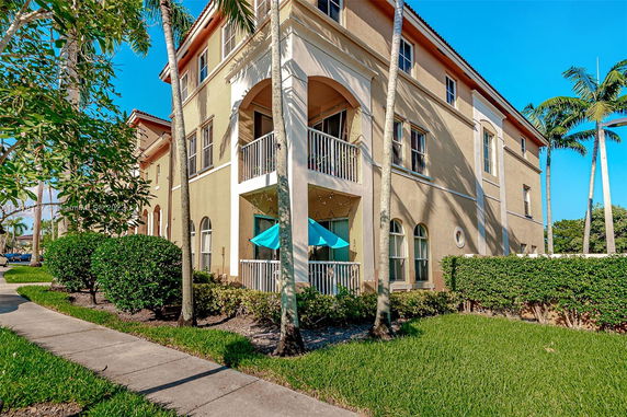Front view of a multi-story residential building with balconies and arched windows.