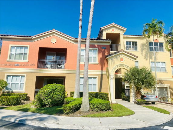 Front view of a multi-story residential building with balconies and an arched entrance.