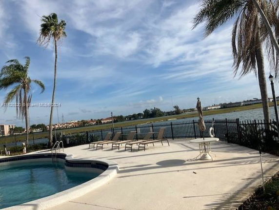 Outdoor swimming pool area with lounge chairs and a view of a lake and surrounding landscape.