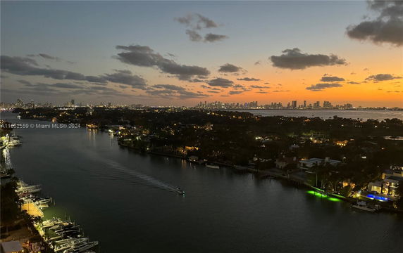 Panoramic view of waterfront buildings and city skyline at sunset.