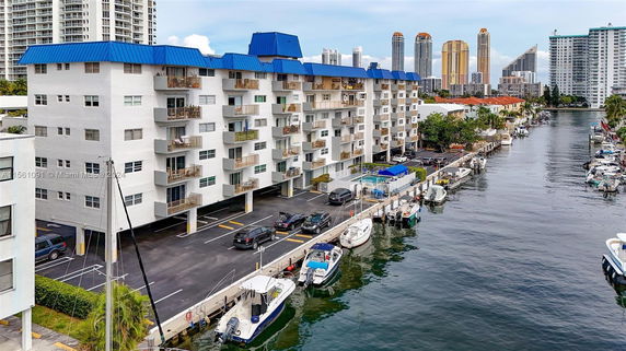 View of a multi-story building with balconies alongside a canal with boats.