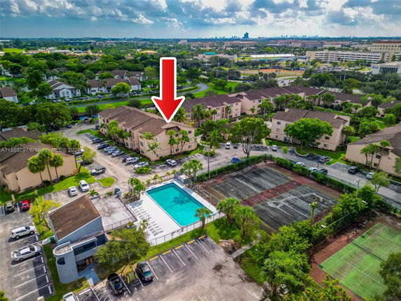 Aerial view of an apartment complex with a swimming pool and tennis courts.