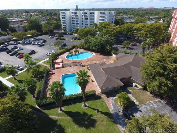Aerial view of a residential complex with two swimming pools and surrounding greenery.