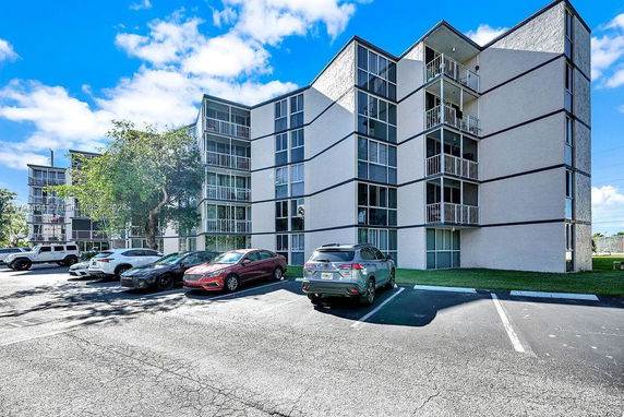 Front view of a multi-story residential building with a parking area in front.