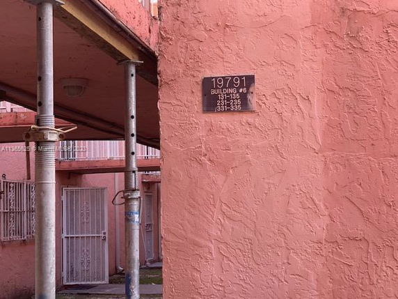 Exterior view of a building with a textured pink wall and a door at the corner.
