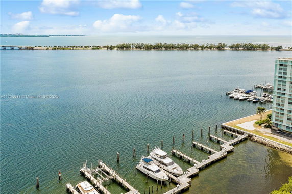 Panoramic view of a marina with boats docked and a distant view of water and a thin strip of land.