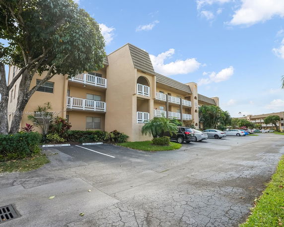 Front view of a multi-story apartment building with balconies and parking area.
