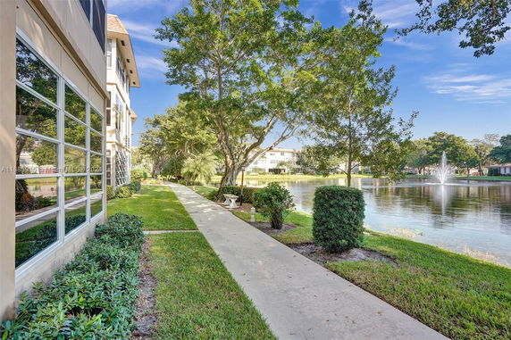 View of landscaped area with a walkway beside a building and a water feature with a fountain.