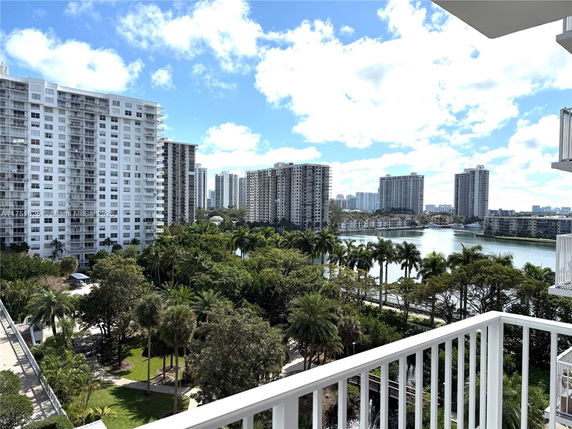 Panoramic view of high-rise residential buildings surrounding a lake, seen from a balcony.