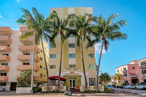 Front view of a multi-story hotel building with palm trees at the entrance.