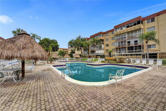 Outdoor view of a swimming pool area with adjacent multi-story buildings.