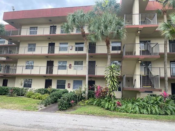 Front view of a multi-story residential building with balconies and palm trees.