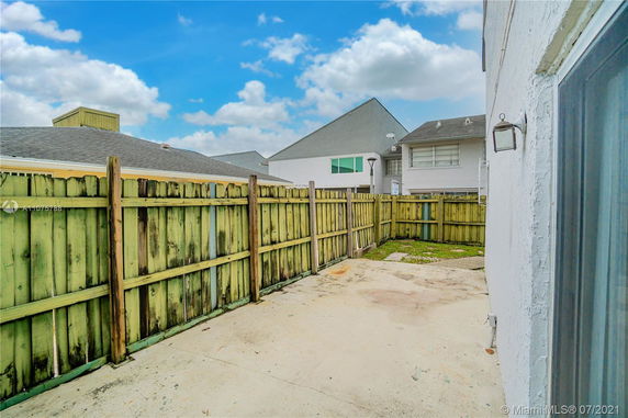 View of a patio area with a wooden fence and adjacent houses.