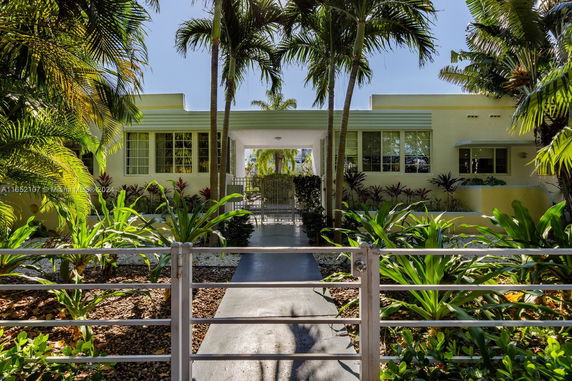 Front view of a house with multiple windows and greenery.