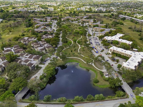 Aerial view of residential buildings and a pond surrounded by greenery.