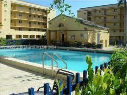 Outdoor swimming pool area in front of a multi-story building.