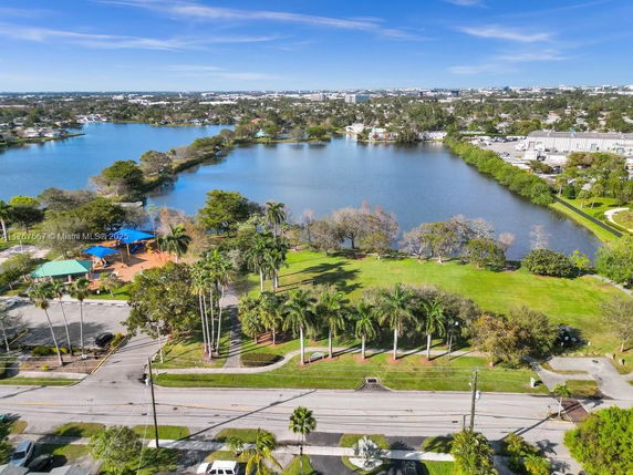 Aerial view of a large lake surrounded by greenery and a suburb in the background.