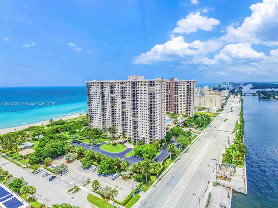 Aerial view of a large seaside apartment building near a coastal road.