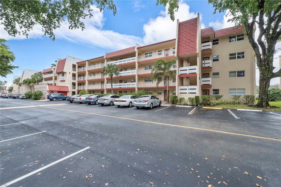 Front view of a multi-story residential building with balconies and parking area.