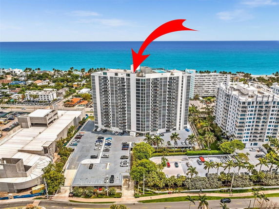 Aerial view of high-rise buildings near the ocean with parking areas and surrounding neighborhood.