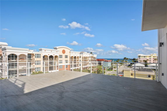 View of surrounding buildings and ocean from a rooftop terrace.