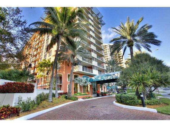 Front view of a multi-story building with balconies and palm trees.