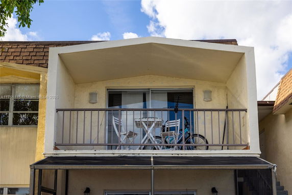 Front view of a house with a small balcony and seating area.