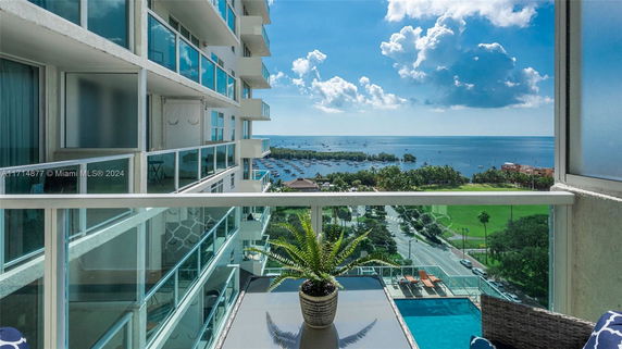 Balcony view from high-rise building overlooking a marina and ocean.