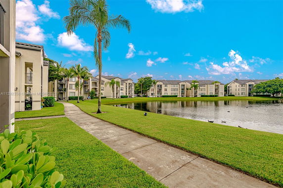 View of apartment buildings with a pond and landscaped areas.