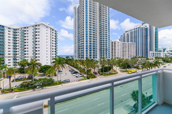 View from a building showing high-rise apartment buildings and a road with palm trees.