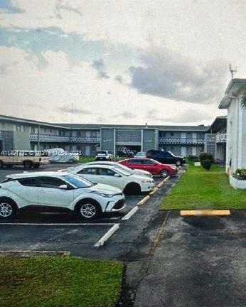 Outdoor parking area with several cars parked in front of a building.
