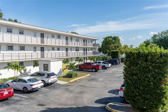 Outdoor parking lot in front of a three-story residential building.