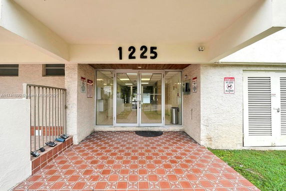 Front view of a building entrance with glass doors and a tiled walkway.