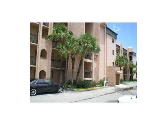 Front view of a multi-story residential building with balconies and palm trees.