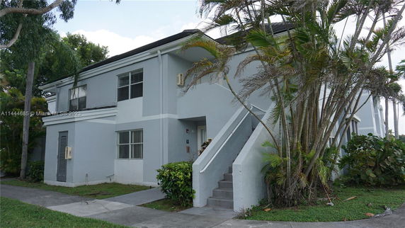 Front view of a two-story building with an external staircase and large windows.