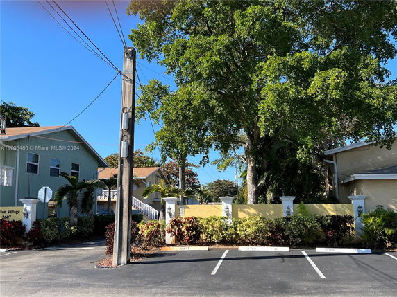 View of a parking area with adjacent residential buildings and landscaping.