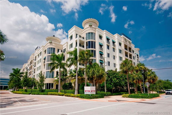 Front view of a multi-story residential building with balconies and large windows.