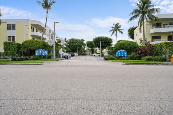 Front view of a multi-story residential building with palm trees.