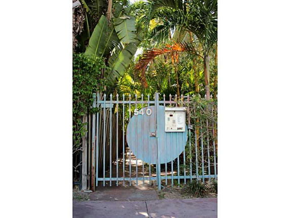 Metal gate entrance with a circular design surrounded by lush tropical foliage.