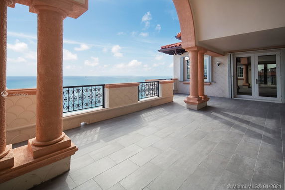 Outdoor terrace with ocean view, featuring decorative pillars and tiled flooring.