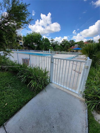 Outdoor swimming pool area surrounded by a white fence.