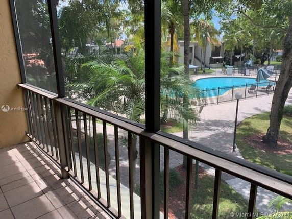 View of the pool area and surrounding trees from a balcony.