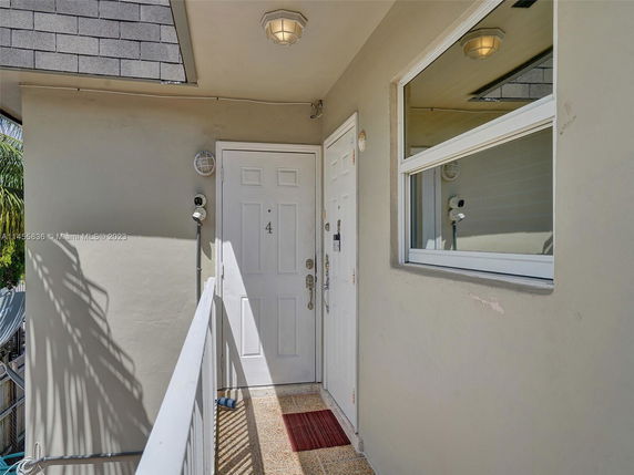 Entrance view of a building with a white door numbered 4 and a window beside it.