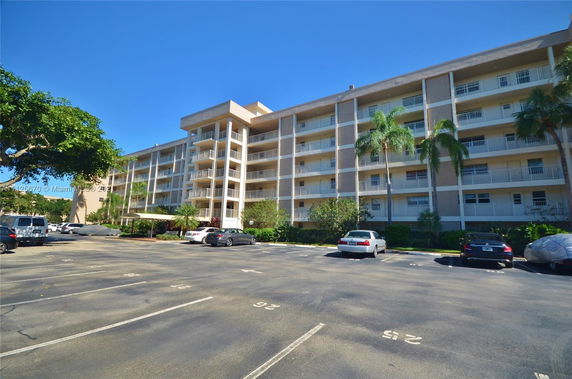 Front view of a multi-story residential building with balconies and parking area.