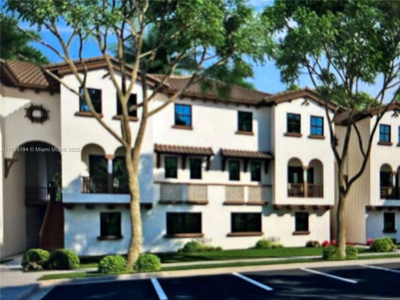 Front view of a multi-story residential building with parking area in front.