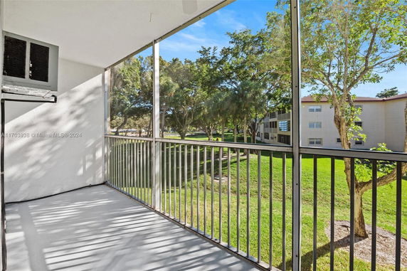 View from a balcony overlooking green space and adjacent buildings.