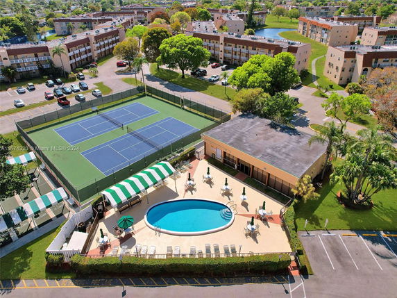 Aerial view showing a recreational area with tennis courts and a swimming pool in a residential complex.