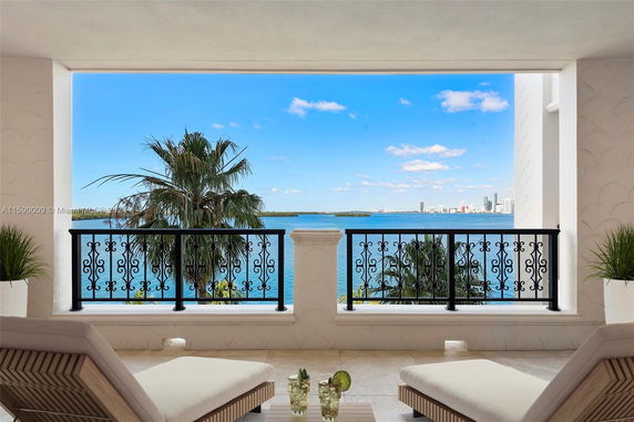 View of the ocean and city skyline from a balcony with ornate railing.