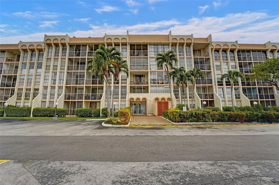 Front view of a multi-story residential building with balconies and large windows.